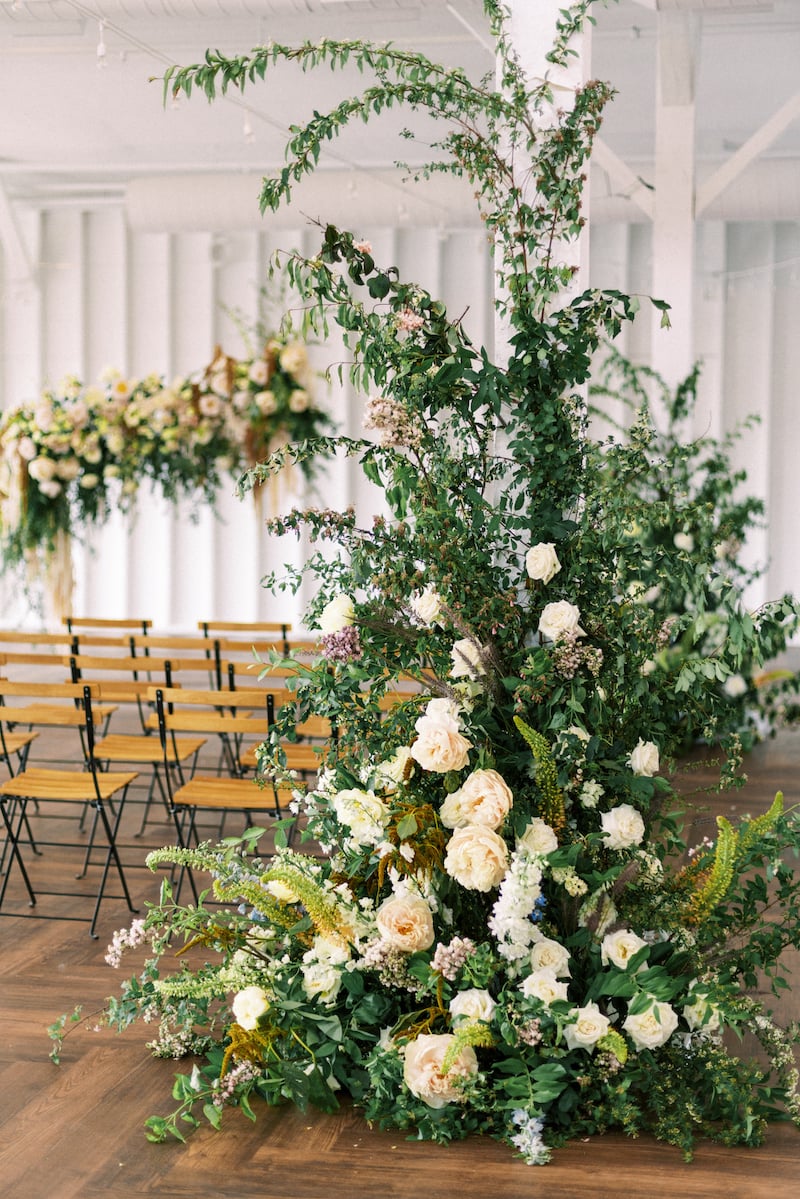 aisleway floral installation featuring eremerus, spirea, tree peonies, delphinium, lilac, roses